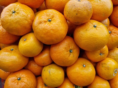 Fresh ripe oranges stacked inp a vibrant display, highlighting bright color and natural texture
