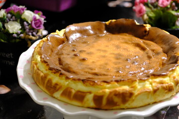 Close-up of San Sebastian Cheesecake. Homemade, toasted, delicious San Sebastian dessert made with cream cheese. Cheese desserts. Delicious San Sebastian and pink roses in a cake display case.
