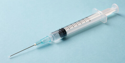 Realistic syringe clear liquid medical syringe hypodermic needle light blue background vaccination equipment