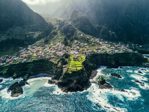 Aerial view of Seixal village on Madeira Island, Portugal, with white houses on green cliffs overlooking the Atlantic Ocean.  
