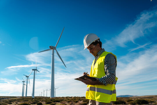 Engineer checking wind turbine performance at renewable energy site, Spain