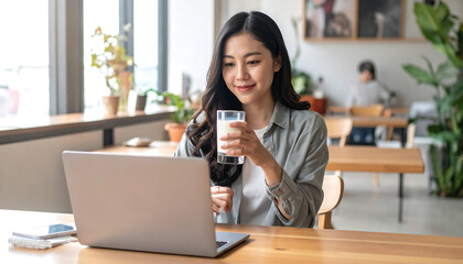A young girl working her remote job in the cafe while enjoying a glass of milk