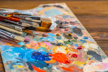 Obraz premium Old used brushes in an artist's studio, palette with multi-colored spots of oil or acrylic paint