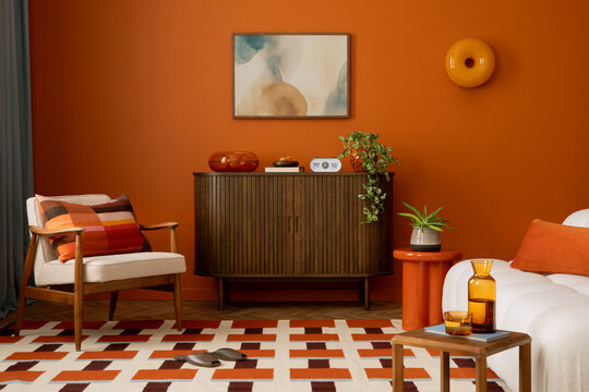 Mid-century inspired living room with orange walls, soft fabrics, and modern art on the wall.