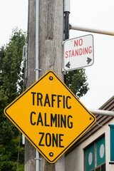 Yellow caution sign warning drivers they are entering a Traffic Calming Zone, to encourage safer, more responsible driving and potentially reduce traffic flow.