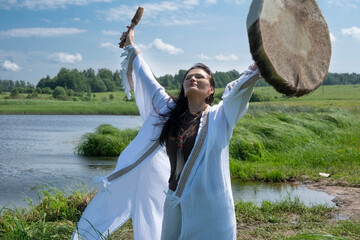 Shaman woman in a trance drumming outdoors