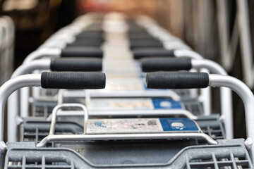 Naklejka premium Supermarket shopping trolley that stacked and group together, ready to service for consumers. Close-up and selective focus at the trolley part. 