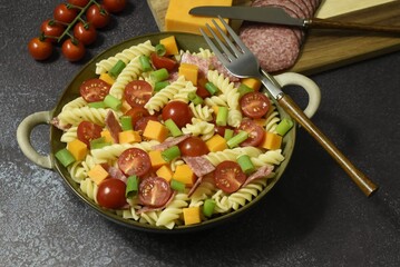 Durum wheat semolina pasta salad made with peppered salami cherry vine tomatoes red leicester cheese spring onions.