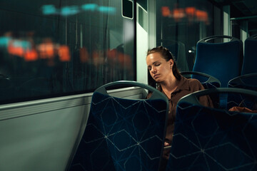 Tired female commuter speeding while traveling by city bus at night © Barillo Images