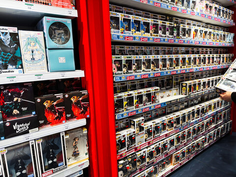 Wide shelf of collectible figures and Funko pops in a bright toy store display