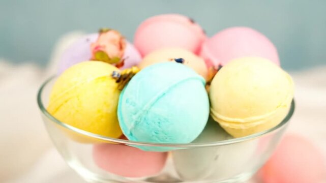 Colorful, round bath bombs in a clear glass bowl, arranged for a natural, spa-like experience