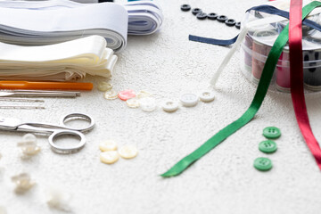 Close-Up of Cufflinks, Sewing Materials, Colorful Threads, and Scissors on a White Surface