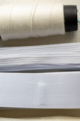 Close-Up of Cufflinks, Sewing Materials, Colorful Threads, and Scissors on a White Surface
