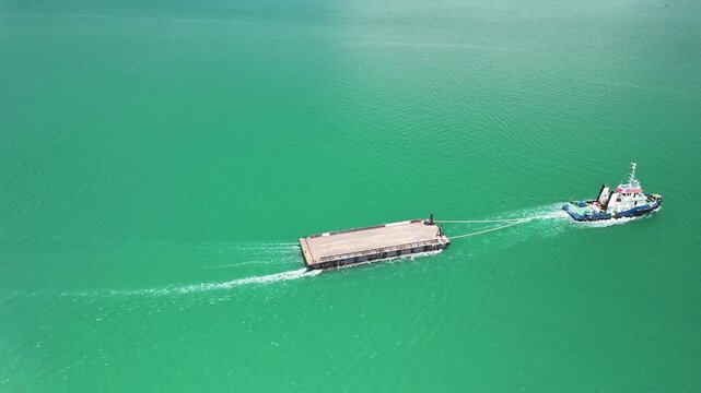 a cargo ship towing a barge across the open sea with distant land and cloudy sky in the background showcasing maritime transport and industrial seascape beauty