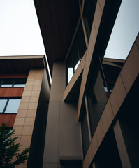 Fototapeta premium Modern architectural design showcasing angular lines and reflective surfaces against a cloudy sky in an urban setting