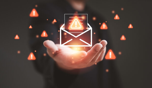 Spam concept showing a businessman holding a glowing envelope with warning icons representing junk mail phishing scam alert email risk data protection and cybersecurity awareness