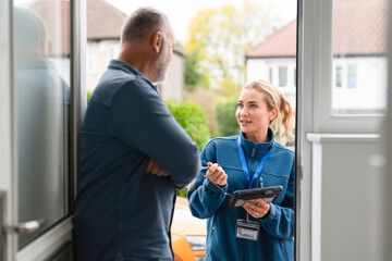Service professional discusses options with a homeowner at the entrance of a house on a sunny day