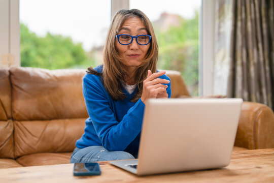 Woman in blue sweater engaged in online conversation at home during daytime