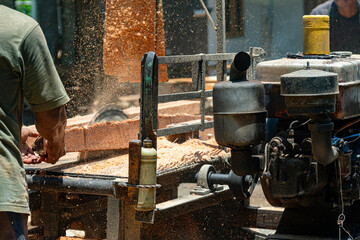 Carpenter Cutting Wood with Saw Machine and Flying Sawdust in Workshop