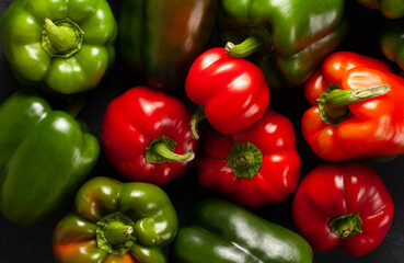 Top view of vibrant red and green bell peppers arranged on a dark surface. Fresh organic vegetables perfect for cooking, healthy eating, vegan recipes, and natural food concepts.