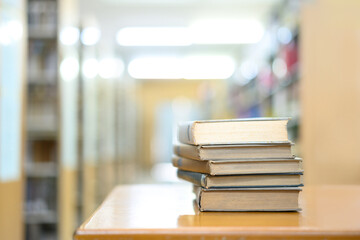 Book stack in the library and blurred bookshelf background for education
