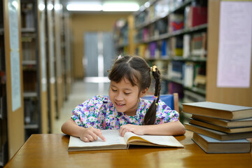 Photo set of Little girl reading aloud from exercise book with joy in school library