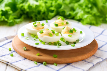 light snack of  hard boiled chicken eggs and mayonnaise on a white table.