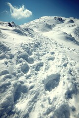 Snowy mountain scene with footprints leading upward under a clear sky