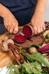 Hands cutting fresh organic beets on wooden table
