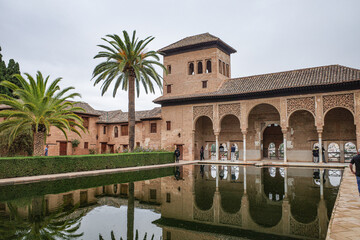 Fototapeta premium Granada, Spain - 21 Oct 2025: Partal Palace and pond at the Nasrid Palaces, Alhambra