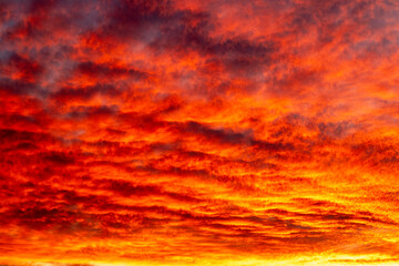 Fiery sunset paints dramatic sky with orange and red clouds over calm horizon