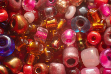 Macro close-up of colorful glass beads and seed beads for handicrafts, background of bright decorative elements