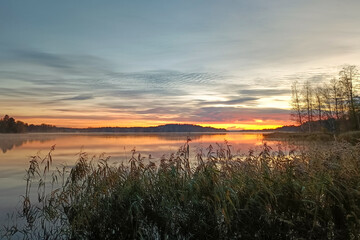 Obraz premium A beautiful sunrise on a calm lake in Finland. A colorful, quiet Finnish morning