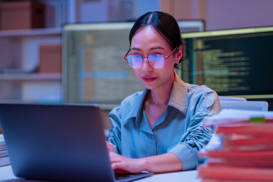 Asian female smart programmer works late night office coding deep learning AI models, training neural networks with intense concentration and focus, dedicating overtime hours alone to machine learning