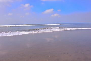 Expansive seascape of Cox's Bazar beach on the Bay of Bengal in Bangladesh, with a vast blue sky and gentle waves.