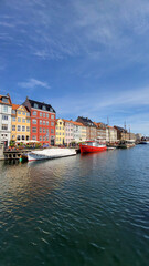 07 August, 2024, Copenhagen city center, Denmark Summer day scenic canal with boats and tourists, cyclists riding along colorful buildings and waterfront, vibrant urban atmosphere in European capital