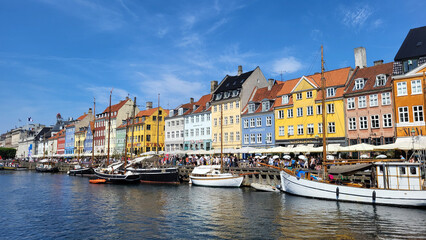 07 August, 2024, Copenhagen city center, Denmark Summer day scenic canal with boats and tourists, cyclists riding along colorful buildings and waterfront, vibrant urban atmosphere in European capital