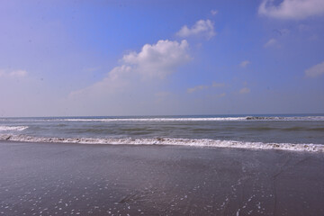 Obraz premium The scenic view from Laboni Point, a popular tourist spot on Cox's Bazar beach. Calm waves of the Bay of Bengal meet the sand under a beautiful blue sky. A perfect Bangladesh travel image.