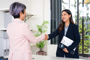 Business people job interview by HR officer shaking hands in office smiling face with happiness. Manager Businesswoman interview employee face to face sitting in meeting room. Job Interview Concept.