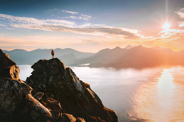 Man travel in Norway climbing mountains enjoying sunset aerial sea view in Lofoten islands,...