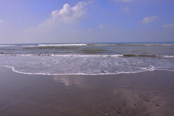 Expansive seascape of Cox's Bazar beach on the Bay of Bengal in Bangladesh, with a vast blue sky and gentle waves.