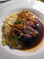 a white dish of beef tenderloin in truffle sauce accompanied by risotto