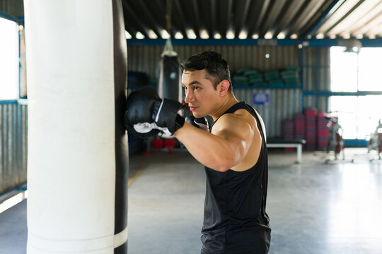 Latin man boxing punching bag in gym workout