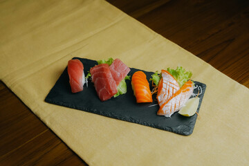 Freshly Prepared Assorted Sushi and Sashimi Platter on a Dark Slate Board.