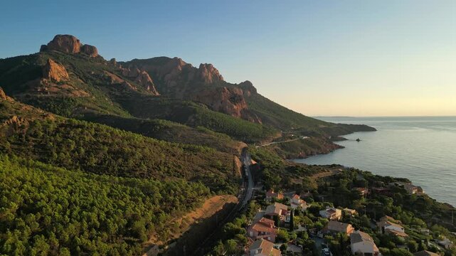 Aerial cinematic view of a train crossing the Antheor Viaduct in the Esterel Mountains near Saint Raphael, French Riviera, overlooking the Mediterranean Sea and luxury villas along the Cote dAzur at s
