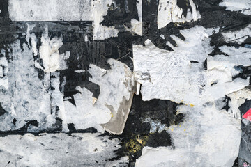 Grunge texture of torn paper layers and worn posters on old wall with rough surface.