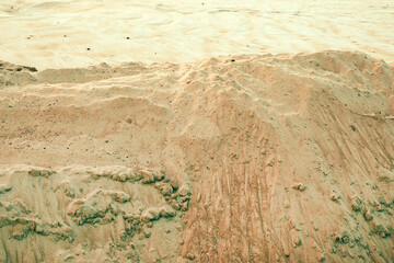 Closeup texture of dry beach sand with natural patterns and small ridges formed by wind and water erosion.