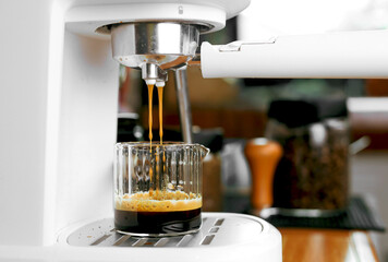 Close-up view of espresso machine pouring fresh coffee into a measuring cup. The process of making coffee with barista equipment.