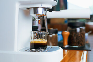 Close-up view of espresso machine pouring fresh coffee into a measuring cup. The process of making coffee with barista equipment.