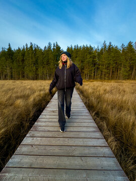 Joyful Young Woman Dancing on Boardwalk in Beautiful Autumn Nature